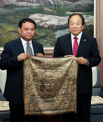韩国釜山广域市议会议长诸宗模（右）代表议会接受喜饶尼玛赠送的礼物。