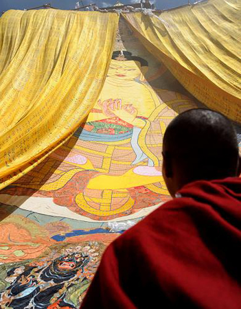 一名僧人注视着甘丹寺展出的巨幅唐卡